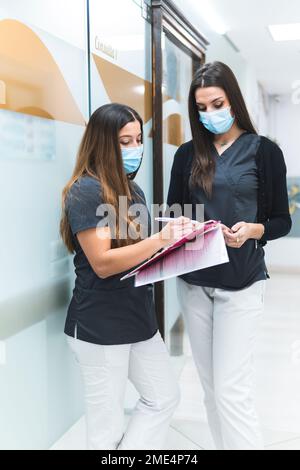 Dental assistants discussing over documents standing at clinic Stock Photo