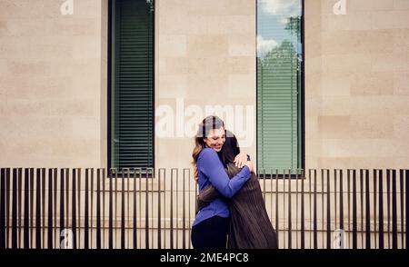 Happy businesswoman hugging colleague standing in front of building Stock Photo