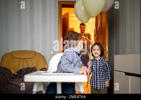 Cheerful boy with father celebrating son's birthday at home Stock Photo