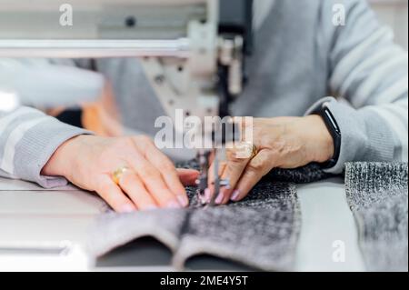 Senior craftswoman using sewing machine in workshop Stock Photo