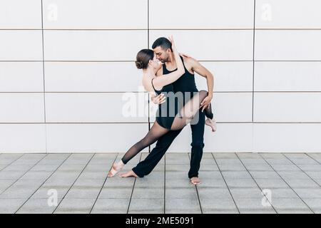 Couple performing ballet dance in front of wall Stock Photo