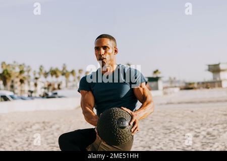 Man exercising with medicine ball on beach Stock Photo