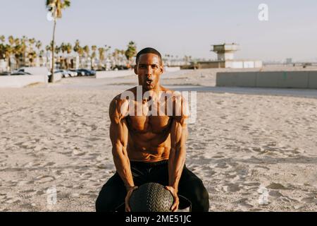 Active man exercising with sports ball on beach Stock Photo