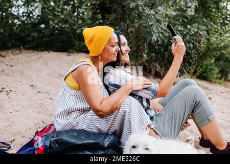 Happy women taking selfie through smart phone at park Stock Photo