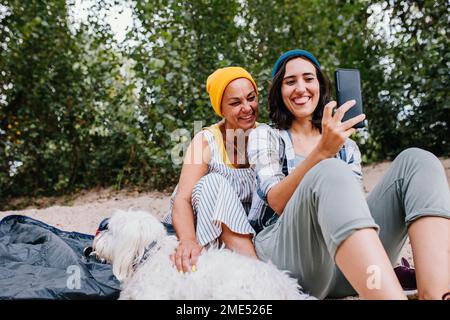 Happy women taking selfie through mobile phone at park Stock Photo