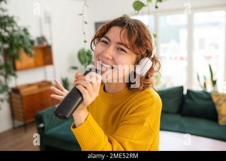 Happy young woman singing at home Stock Photo