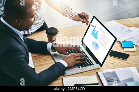 The stats prove their success. two businesspeople analyzing graphs on a laptop in an office. Stock Photo