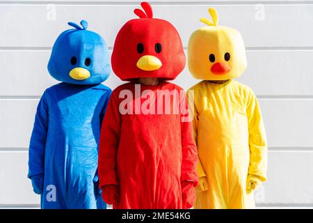 Friends wearing multi colored costumes standing in front of white wall Stock Photo