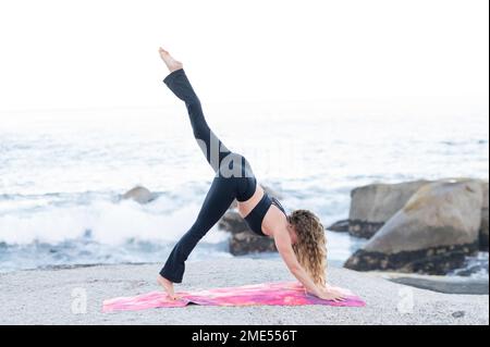 Woman practicing yoga at beach Stock Photo