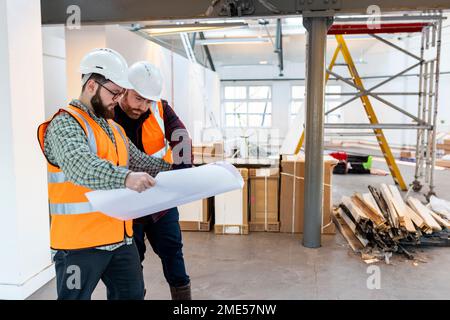 Young engineers discussing over blueprint at construction site Stock Photo