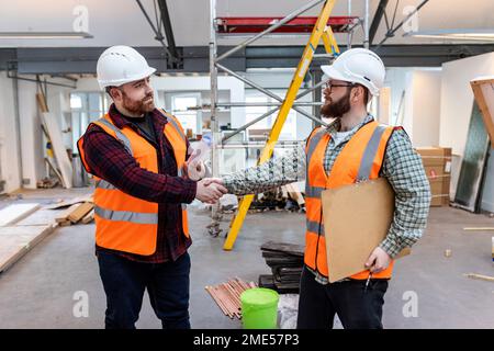 Young engineers shaking hands with each other at construction site Stock Photo