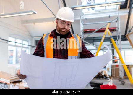 Young engineer examining blueprint at construction site Stock Photo