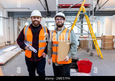Smiling young engineer standing with colleague at construction site Stock Photo