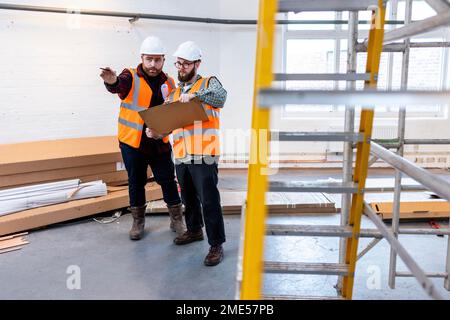Young engineers examining and discussing over document at construction site Stock Photo