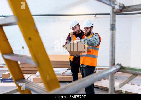 Engineers wearing hardhats having discussion over document Stock Photo
