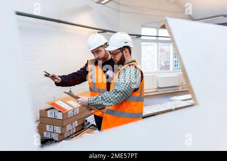 Engineers examining and discussing over document at construction site Stock Photo