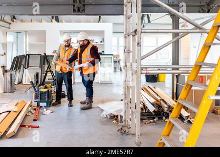 Engineers having discussion over document at construction site Stock Photo