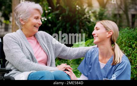 Thank you for all of your help. a cheerful elderly woman in a wheelchair spending time with her daughter outside in a park. Stock Photo