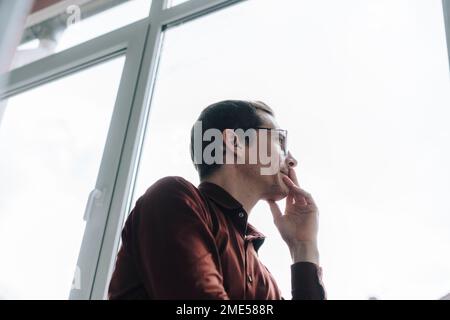 Thoughtful businessman looking through window Stock Photo