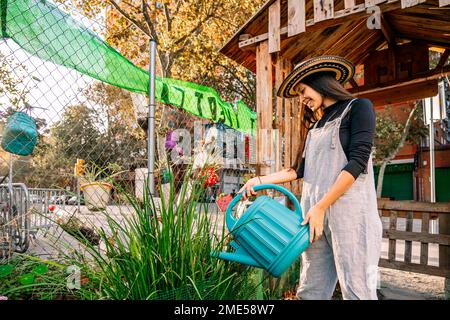 Happy young woman watering plants in garden Stock Photo