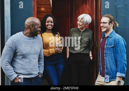 Hes always the topic of discussion. a group of businesspeople having a discussion together while standing outside of their office building. Stock Photo