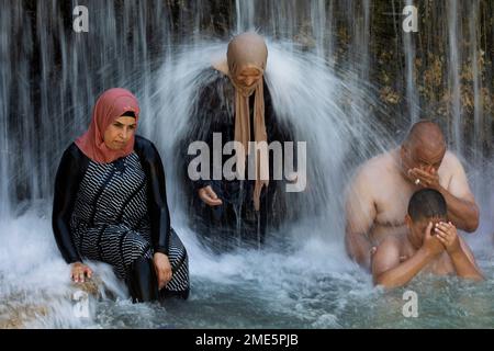 Israeli Arabs stand under a waterfall during the Muslim Eid al Adha