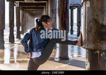 Smiling woman doing stretching exercises outdoors. Stock Photo