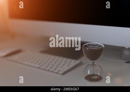 Hourglass on laptop keyboard. Time management concept Stock Photo