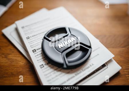 Paris, France - Jan 16, 2023: Nikon lens cover above instruction manual of a new DSLR Mirrorless lens Stock Photo