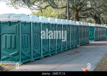 Row of green portable potty outhouses ready for use at a concert, festival, or event Stock Photo