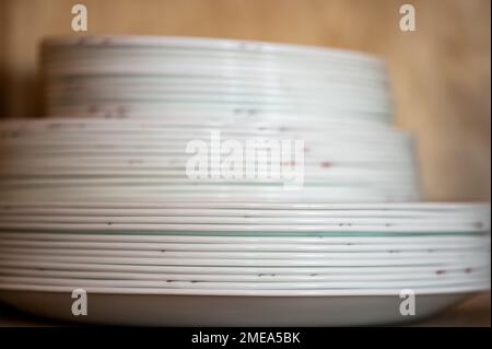 Narrow depth of field picture of an open kitchen cabinet stacked ceramic plates and bowls. Stock Photo