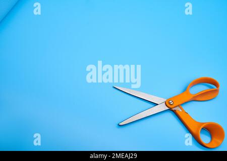 Orange shear scissors on a light blue background cutting shears baby blue Stock Photo