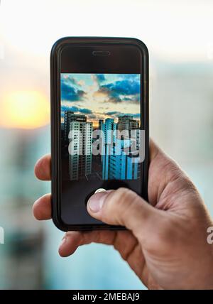 I travel with my cellphone for so many reasons. an unrecognizable man taking a photo of the city with his cellphone outside. Stock Photo