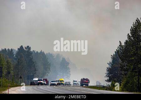 Cars drive through smoke away from a forest fire about 18 km 11.3