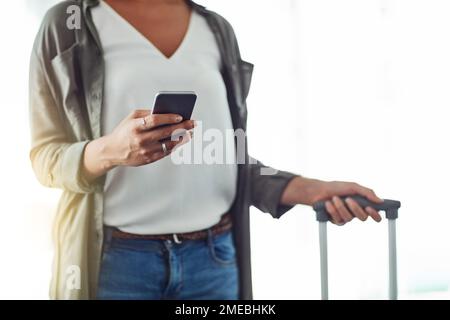 Looking up whats cool in this destination. an unrecognizable woman using a cellphone in an airport. Stock Photo