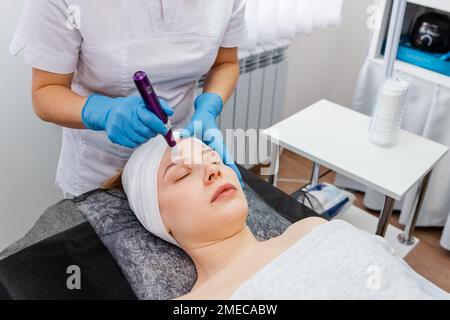 Dermatologist making mesotherapy injection with dermapen on face Stock Photo