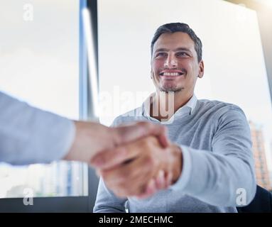 Im glad to see this merger through. two businessmen shaking hands in an office. Stock Photo