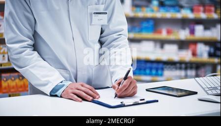 Everything goes on record. Closeup shot of an unrecognizable pharmacist writing on a clipboard in a pharmacy. Stock Photo