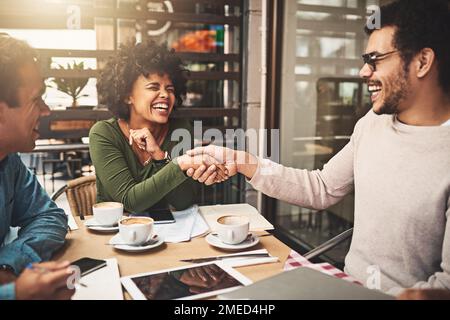Thank you for the opportunity. two cheerful young work colleagues shaking hands after an successful meeting at a coffeeshop during the day. Stock Photo