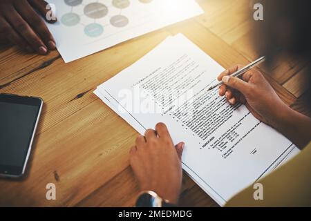 Making sure she doesnt miss a thing. a businesswoman completing paperwork at a desk. Stock Photo