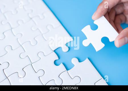 White jigsaw in the hands, The correct solution. Teamwork, Solving and completing the task. Last piece of jigsaw puzzle. Assembling jigsaw puzzle piec Stock Photo