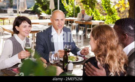 Two happy couples having lunch at open-air restaurant summer Stock Photo