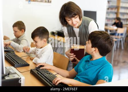 Woman teacher helping boy in computer room Stock Photo