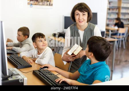 Woman teacher helping boy in computer room Stock Photo