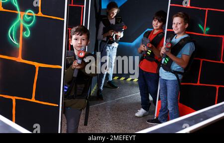 boy aiming laser gun at other players during lasertag game Stock Photo