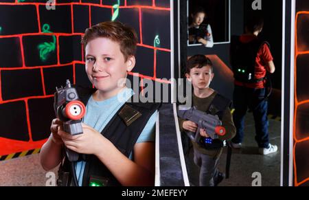 Foto Stock Excited boy aiming laser gun at other players during