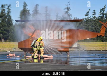 Aviation Boatswain's Mate- Aircraft Handling 2nd Class Dakota Montoya and Aviation Boatswain's Mate- Aircraft Handling 1st Class Michael Flosi assigned to Navy Region Northwest Fire and Emergency Services put out a fire during an aircraft mishap drill on the Naval Outlying Field in Coupeville, Washington August 17, 2022. The joint training tested the aircraft mishap response procedures of our Federal Fire, Search and Rescue, and local first responders. Stock Photo