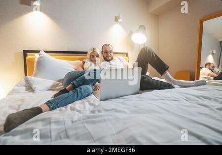 Young couple lying on couch at home looking at laptop. Stock Photo