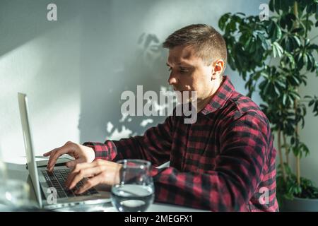 Portrait of cheerful freelancer man working on laptop computer in cafe. Stock Photo