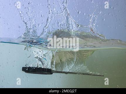 scissors fall into the water. sprays, drops and bubbles Stock Photo